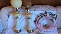 Three lamps together showing two amber glass post lamps with globe shades and one pink decorative circular lamp.