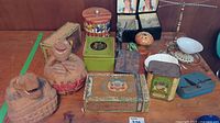 Overview of various decorative boxes, tins, figurines, and containers arranged on wooden surface.