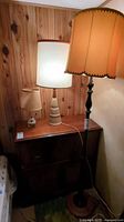 Photo of all three lamps: one tall floor lamp and two shorter table lamps on wood furniture against wood paneled wall.