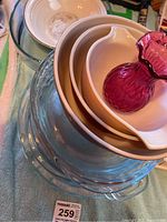 Full view of all items including Pyrex bowls, clear pie plates, Royal Doulton bowl, and cranberry glass vase on top