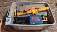 Bin with vintage train set components including yellow crane car and transformer box