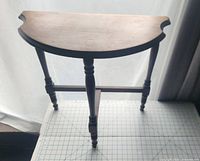 Front view of antique half moon wood table showing crescent cutouts on sides and turned legs.