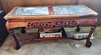 Front view of the hardwood coffee table showing marble top and carved wooden apron