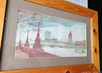 Framed watercolor painting showing London landmarks under glass with a natural wood frame and gray matting.