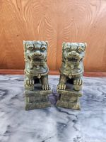 Front view of the two carved Foo Dogs seated on rectangular bases, showing detailed faces and paws.