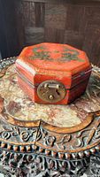 Overview of the octagonal Asian dragon trinket box on a carved wooden table, showing the brass clasp.
