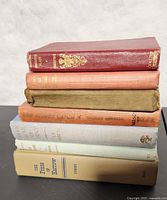 Stack of seven old books showing spines and general condition.