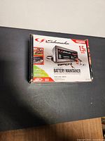 Front view of boxed Schumacher battery maintainer showing brand, model, amperage and product image.