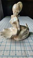 Front angled view of vintage ceramic mermaid soap dish showing iridescent glaze and mermaid figure with tail forming the dish.