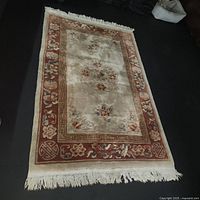 Full view of rug laid flat on dark floor showing overall pattern and fringe