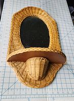 Top-down view showing wicker frame, oval mirror, wooden shelf, and curved woven basket attached underneath.