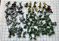 Top view photo of 74 toy soldiers in multiple colors and 1 red cannon, displayed on a grid background to show scale and quantity.