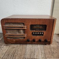 Front of 1940s Wards Airline short wave radio showing frequency dial, control knobs, speaker grill with wooden slats and cloth.