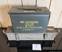 Green ammo can with yellow stencil writing showing ammunition details and contents.