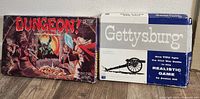 Photo showing both board game boxes: Dungeon! Fantasy Board Game by TSR with fantasy artwork and Gettysburg Civil War Game by Avalon Hill with cannon image and blue/white design.