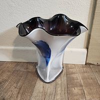 Side view showing the vase height and blue brush stroke accents on frosted white glass with black top edges.