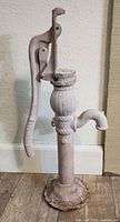 Front-side view of the vintage cast iron water pump showing the full handle and spout.