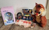 Entire lot showing various Disney and Lego items including large Chip plush, Disney Princess anniversary clock box, Lego Dimensions packs, and paper materials