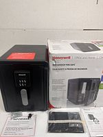Front angle view of the Honeywell waterproof fire safe with box and included accessories (keys, mounting hardware, manual).