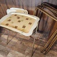 Eight mid-century fiberglass TV trays and legs arranged against a wood background, some trays stacked, showing shape and design.
