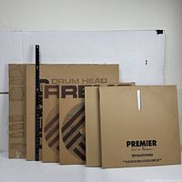 Photo showing 6 drum heads in their original sleeves from Remo, Premier and Aquarian brands lined up.