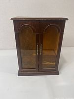 Front view of small wooden jewelry cabinet with two amber glass doors