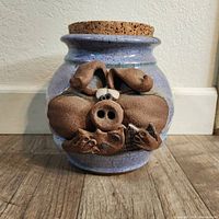 Front view of vintage ceramic cookie jar with pig face and cork lid on top
