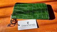 Front view of green crocodile pattern leather wallet with brand logo and tag