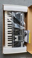 Creative Prodikeys PC-MIDI USB keyboard in original box with protective foam and manual, visible through plastic wrapping.
