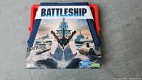 Front of the new Hasbro Battleship board game box, showcasing naval battle imagery and Hasbro branding.