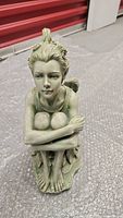 Front view of large resin garden fairy statue showing detailed face and crouching posture