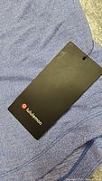 Close-up photo showing black Lululemon tag on blue fabric confirming brand and new condition