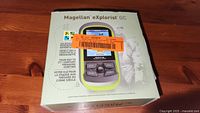 Front view of Magellan eXplorist GC GPS box showing product image and geocaching branding
