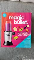 Front of box shows Magic Bullet blender with purple smoothie and fresh fruit images, highlighting the product and accessories inside.