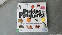 Front of Pickles to Penguins game box showing game title and colorful images representing game theme.
