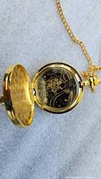 Opened view of gold pocket watch showing inner watch face with Sailor Moon and celestial design