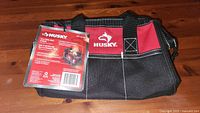Small black and red Husky tool bag with attached product tag showing front and logo.