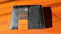 Front view of the new Tracker men's black leather wallet with original label attached showing RFID protection branding.
