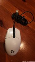 Top view of white Logitech G203 Prodigy mouse showing buttons, logo, and USB cable end