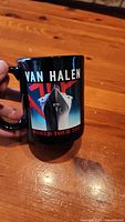 Black ceramic Van Halen 2015 World Tour mug shown against wood background with front and handle visible.
