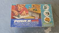 Top view of the box with vintage graphic showing boy using the workshop tools and illustrations of tools included.