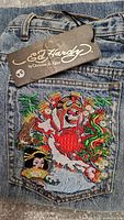 Close-up of Ed Hardy logo tag on jeans back pocket embroidery