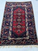 Full view of the hand-knotted Persian Baloch wool rug, showing the entire multi-medallion geometric design in red, blue, and ivory.