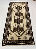 Full front view of rug laid flat on floor showing full geometric pattern in cream and brown.