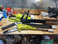 Overview of Ryobi chainsaw power head, 14" bar with scabbard, 10" pole saw attachment and two extension poles on workbench
