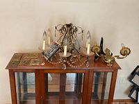 Overall view of chandelier, wall sconce, and switch plates on a wooden cabinet