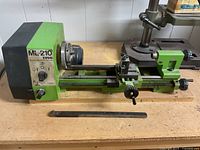 Front left view of lathe on workbench showing headstock, bed, carriage and pry bar