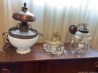 Front view of three vintage lighting fixtures on wooden surface by window curtain