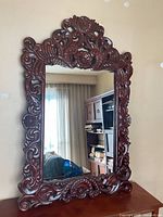 Front view showing the full mirror with detailed ornate wood frame and reflective glass.