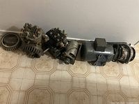 Photo showing assortment of motors and parts laid out on floor, including large gray motor, smaller motors with gearing, and rings.